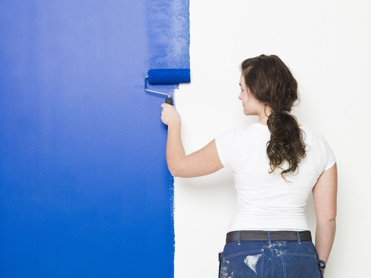 pintora imprimiendo azul con rodillo sobre pared